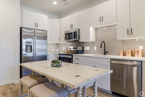 A modern kitchen with a white table and stainless steel appliances.