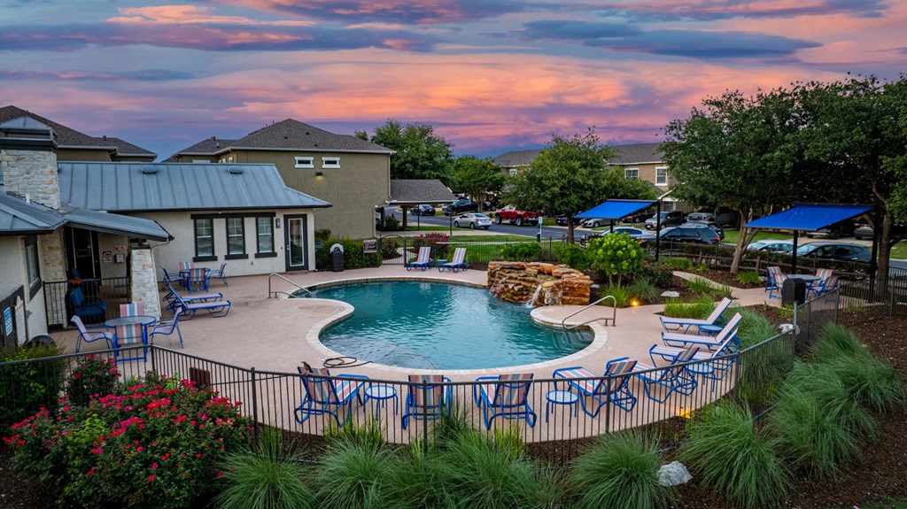 A backyard with a pool and patio furniture.