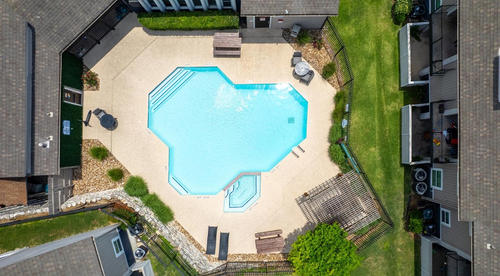 A small swimming pool surrounded by a fence and a small garden.