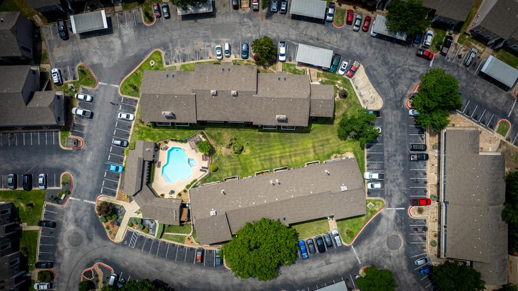 A bird's eye view of a residential area with houses, cars, and a swimming pool.