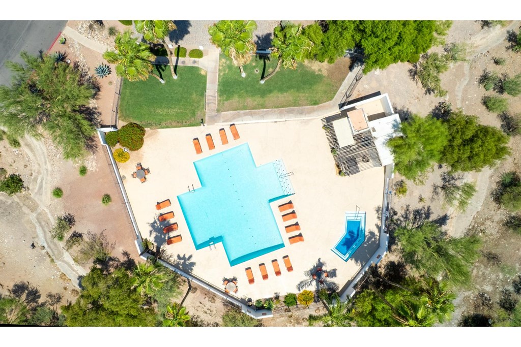 An aerial view of a swimming pool surrounded by trees and a building.