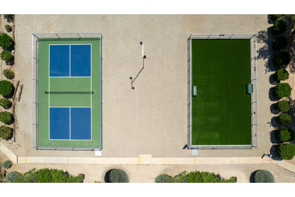 Tennis court surrounded by green bushes.