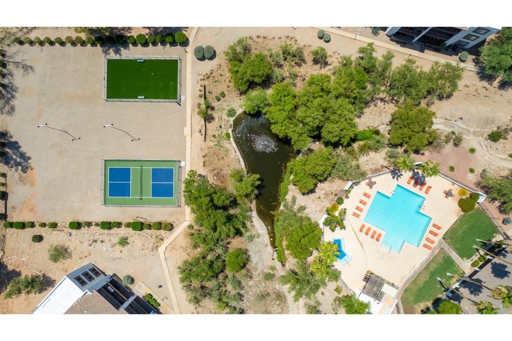 An aerial view of a park with a green field, a blue pool, and a smaller pool with orange stripes.