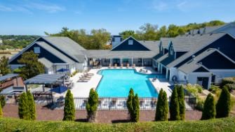 A large swimming pool is surrounded by trees and buildings.