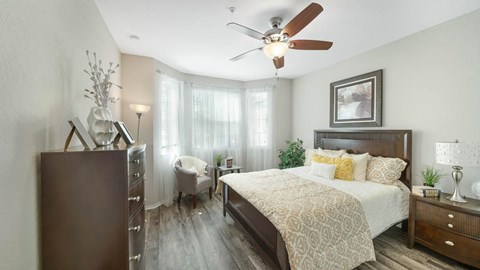 A bedroom with a bed, dresser, and ceiling fan.