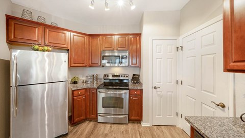 A kitchen with wooden cabinets and a stainless steel refrigerator.