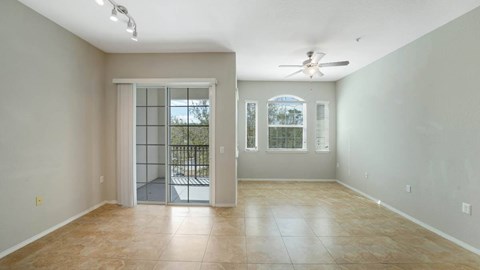 A spacious room with a sliding glass door leading to a balcony.