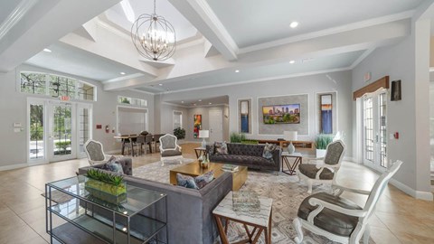 A spacious living room with a glass coffee table and a chandelier hanging from the ceiling.