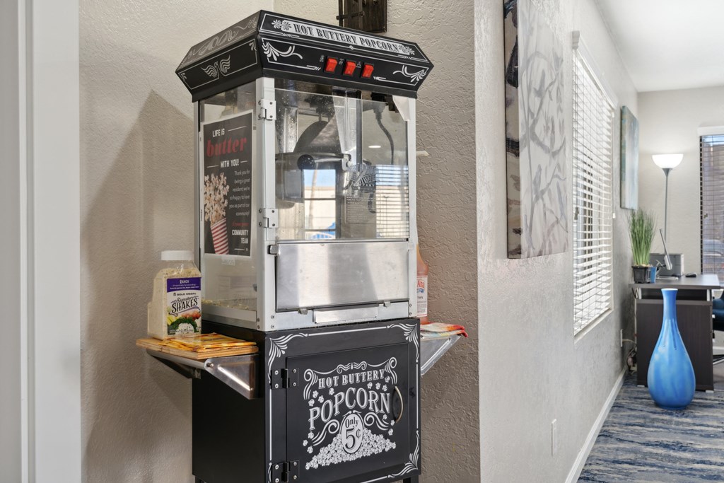 A hot buttered popcorn machine is on a table.