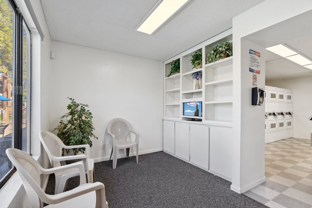 A room with white chairs and a white cabinet with a computer on it.
