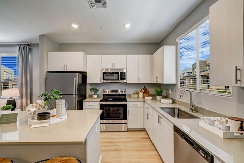 A modern kitchen with white cabinets and stainless steel appliances.