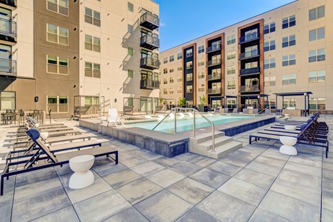 A large outdoor pool area with sun loungers and a small waterfall.