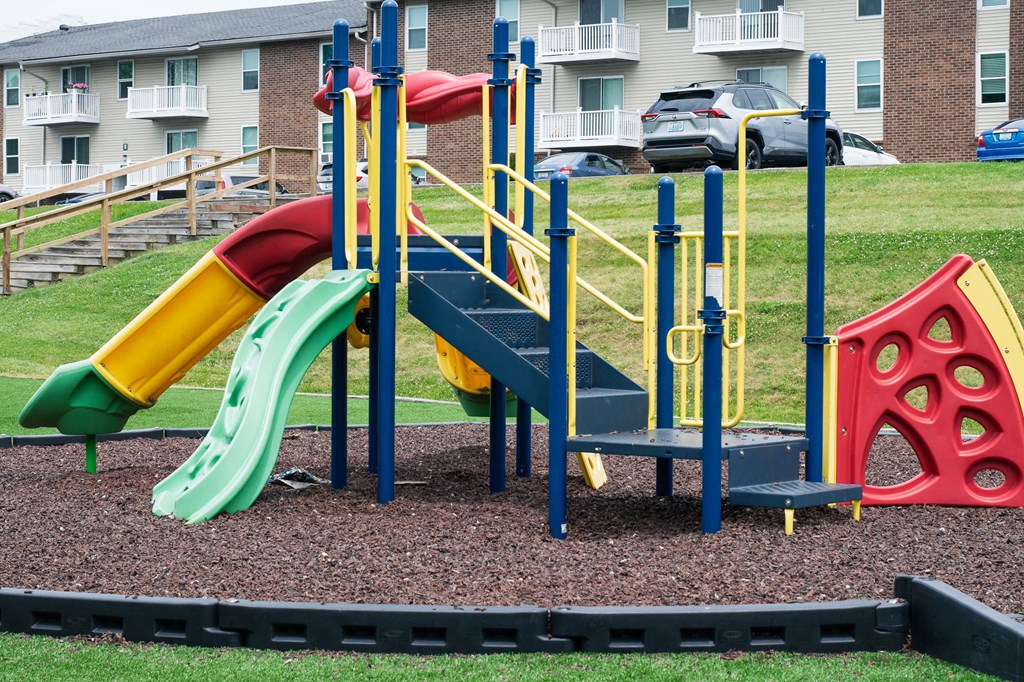 A playground with a green, yellow, and red slide.