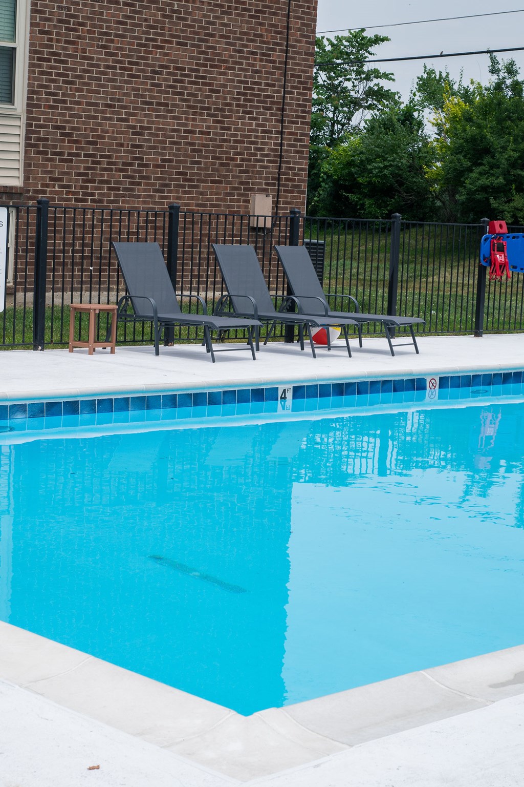 A pool with a black fence and two chairs.