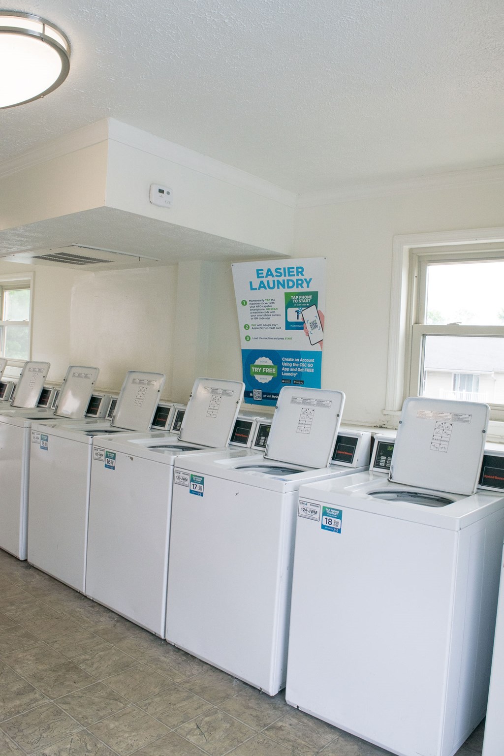 A row of white washing machines are on display in a laundry store.