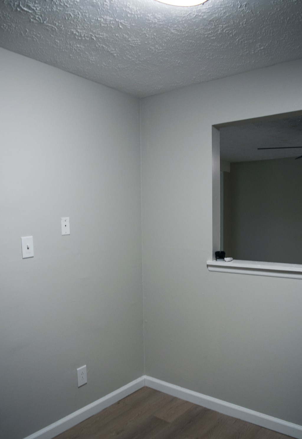 A room with a window and two switches on the wall.