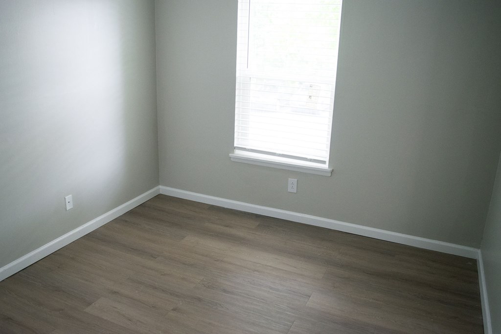 A room with a window and wooden flooring.