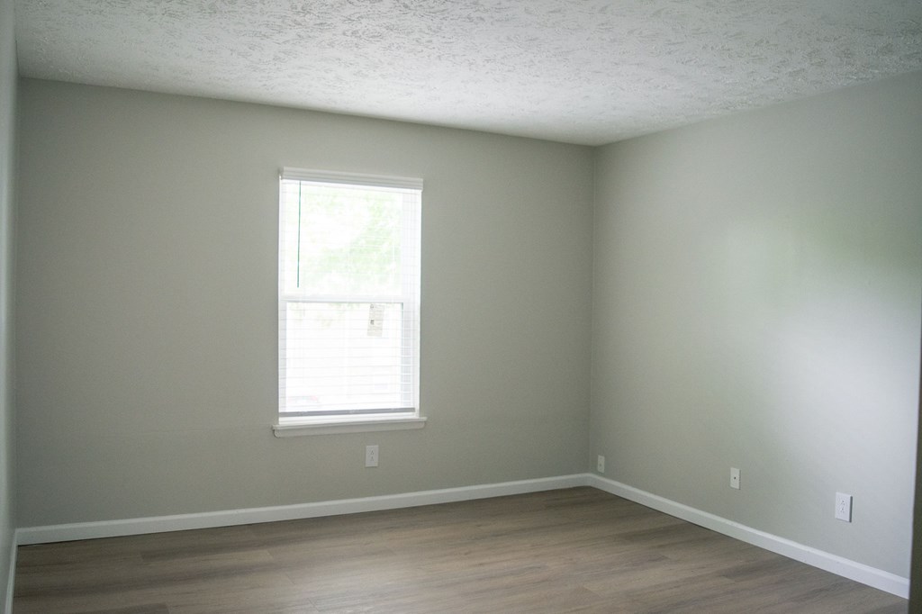 A room with a window and wooden floors.