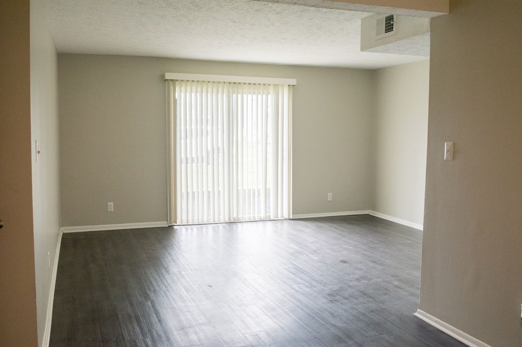 A room with a window covered by white blinds.