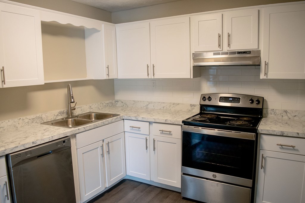 A kitchen with white cabinets and a marble countertop.