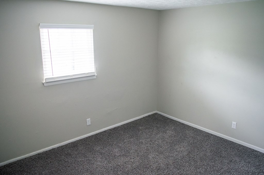 A room with a window and carpeted floor.