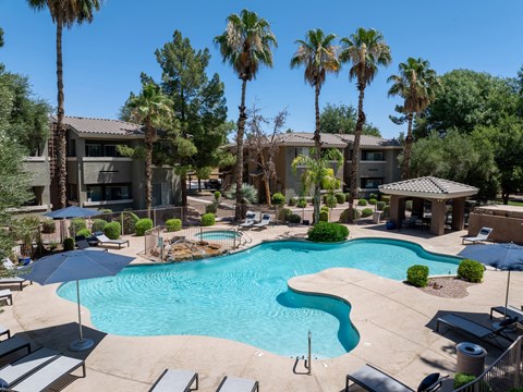 A swimming pool surrounded by palm trees and lounge chairs.