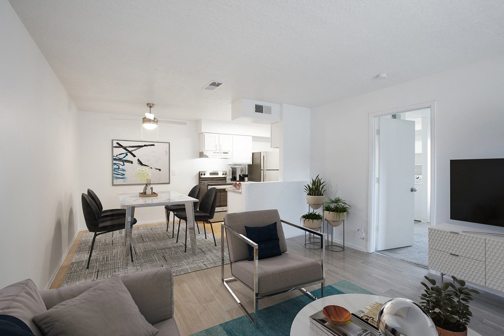 a furnished living room with a dining room table and chairs and a kitchen in the background