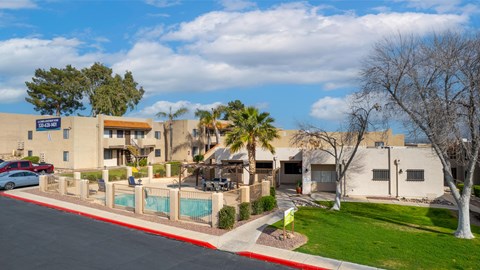 A sunny day at the Sunrise Apartments with a pool and palm trees.