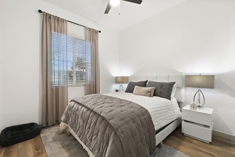 A bedroom with a large bed and a window with curtains.