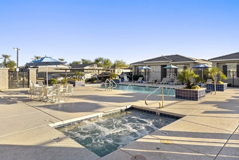 A pool area with a hot tub and lounge chairs.