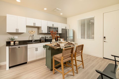 A kitchen with a table and chairs in the middle.