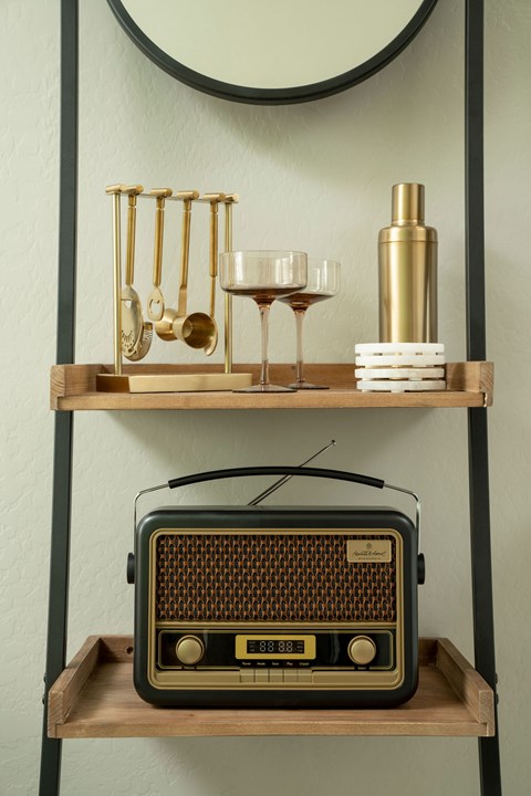 A shelf with a radio, wine glasses, and a bottle.