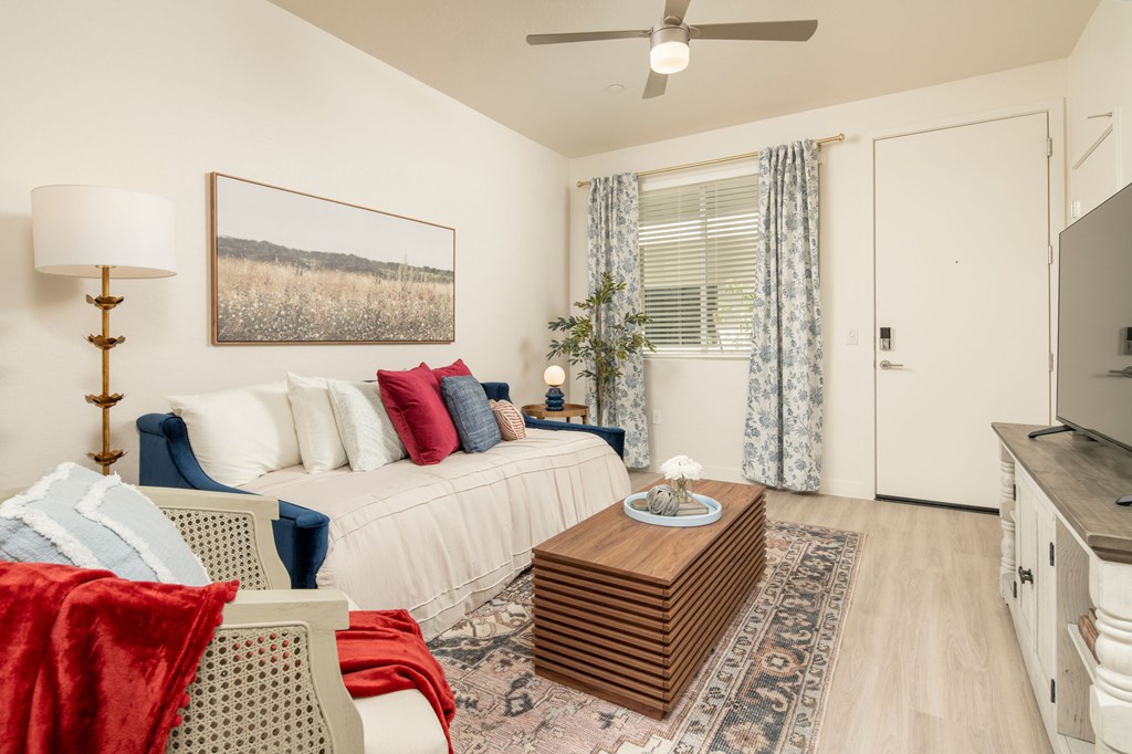 A living room with a white couch, a red blanket, and a painting on the wall.