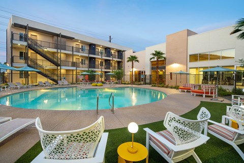 A pool area with chairs and a building in the background.