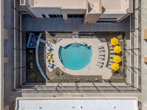 A small pool surrounded by a concrete patio and yellow chairs.