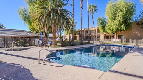 a swimming pool with palm trees and a building in the background