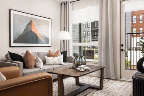 A living room with a grey couch, a brown armchair, a wooden coffee table, and a painting on the wall.