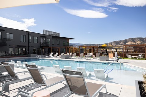 A pool with sun loungers and a building in the background.