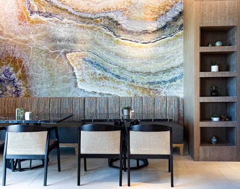 A dining area with a large, colorful wall mural and a wooden shelf.