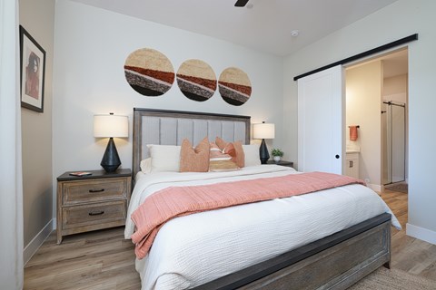 A bedroom with a large bed and a wooden nightstand.