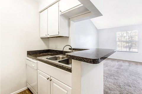 A kitchen with white cabinets and a black countertop.