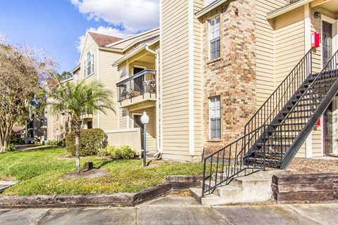 A two-story apartment building with a balcony and a stone pillar.