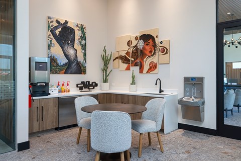 A modern kitchen with a table and chairs and two paintings on the wall.