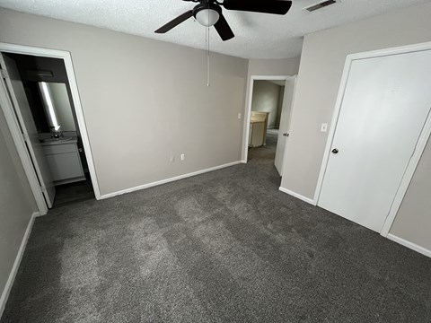 A room with a ceiling fan and carpeted floor.