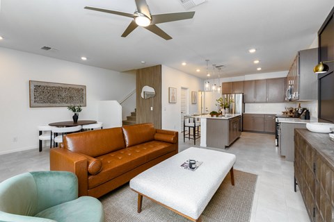 A modern living room with a brown leather couch and a white ottoman.