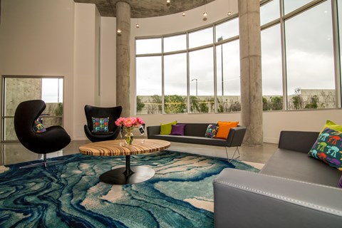 A living room with a blue rug and a grey couch.