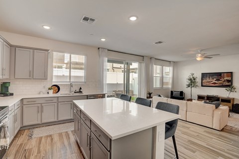 A modern kitchen with a large island and a living area with a couch.