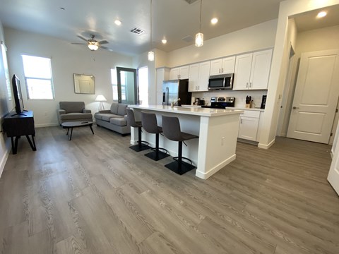 a kitchen and living room with wood floors and white cabinets