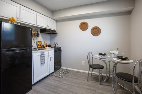 a kitchen and dining area with a black refrigerator and a table and chairs