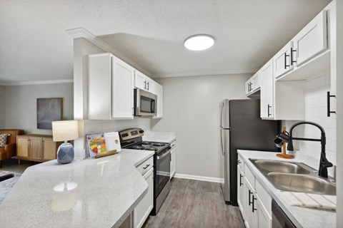 A kitchen with white cabinets and a black fridge.